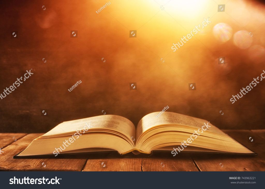 stock-photo-image-of-open-antique-book-on-wooden-table-with-glitter-background-743963221